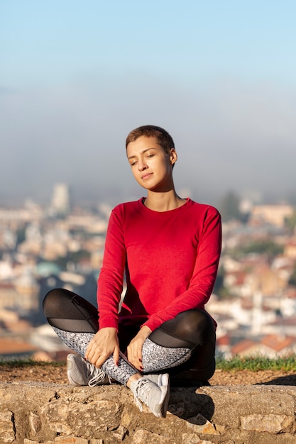 Foto gratuita tiro completo de mujer sentada al aire libre