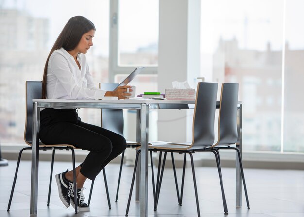 Tiro completo mujer sentada en el escritorio