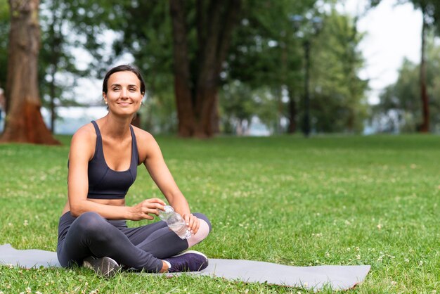 Tiro completo mujer sentada en la estera de yoga