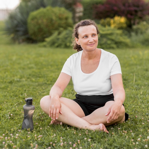 Tiro completo mujer sentada sobre el césped