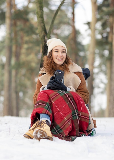 Foto gratuita tiro completo mujer sentada sobre la nieve