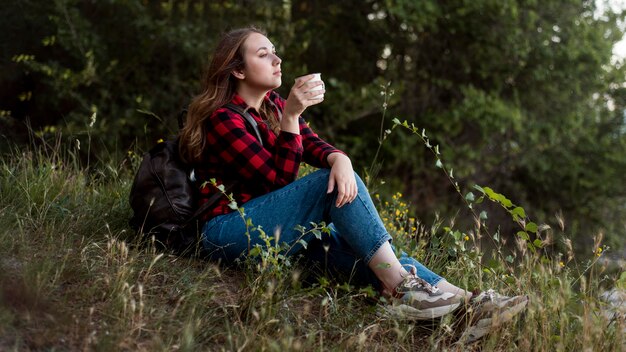 Tiro completo mujer sentada en el suelo en el bosque