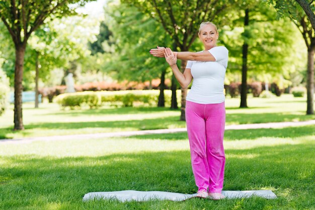 Tiro completo mujer sonriente haciendo ejercicio en la naturaleza