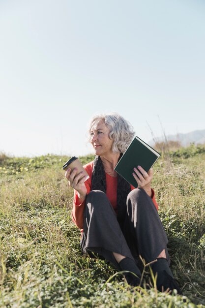 Tiro completo mujer sonriente con libro al aire libre