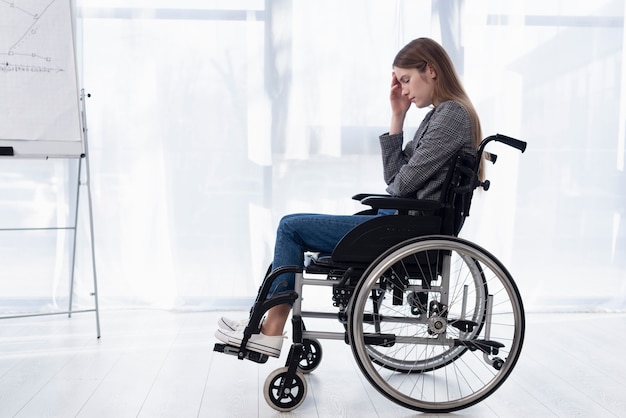 Foto gratuita tiro completo mujer triste en silla de ruedas