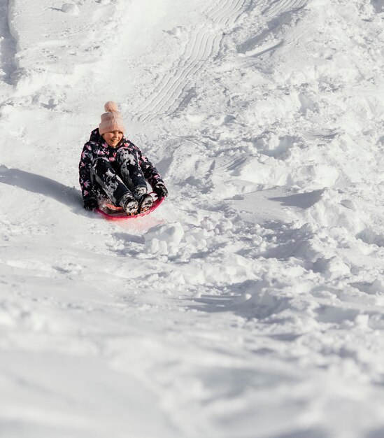 Tiro completo niña feliz en la nieve al aire libre