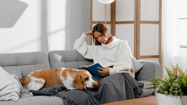 Tiro completo niña leyendo en el sofá