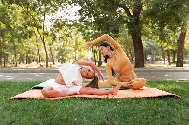 Tiro completo niña y mujer haciendo yoga