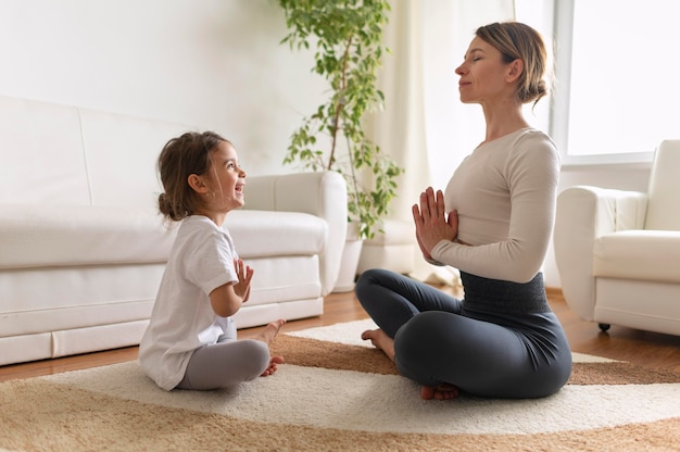 Tiro completo niña y mujer meditando