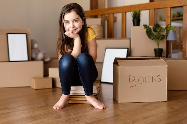 Foto gratuita tiro completo niña sentada en libros