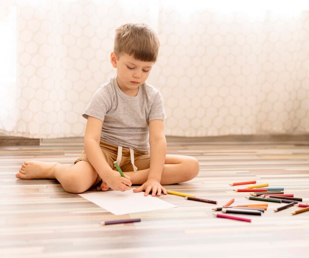 Tiro completo niño dibujando en el piso