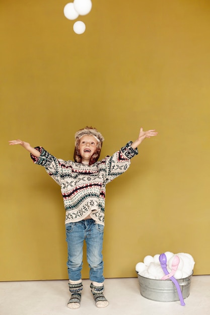 Foto gratuita tiro completo niño jugando con bolas de nieve en el interior