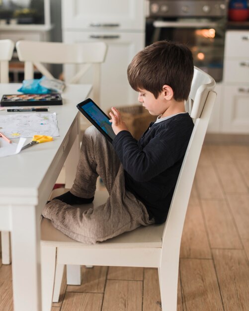 Tiro completo niño en silla con tableta