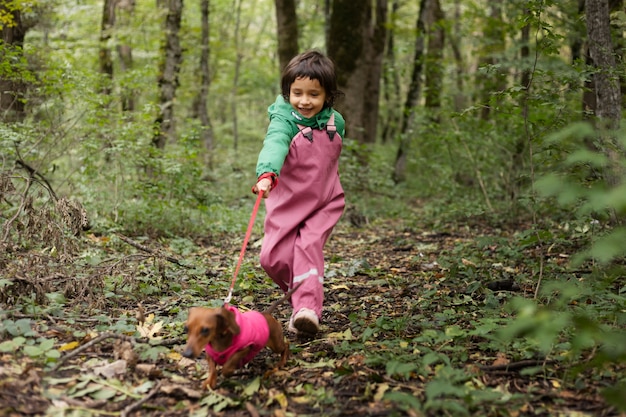 Tiro completo niño sonriente paseando a un perro en la naturaleza