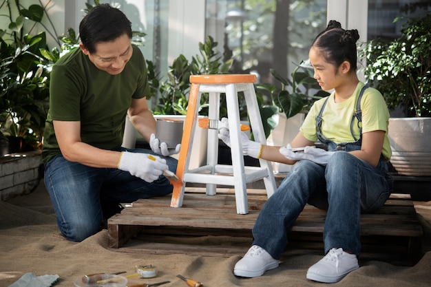 Tiro completo padre y niña pintando silla de madera