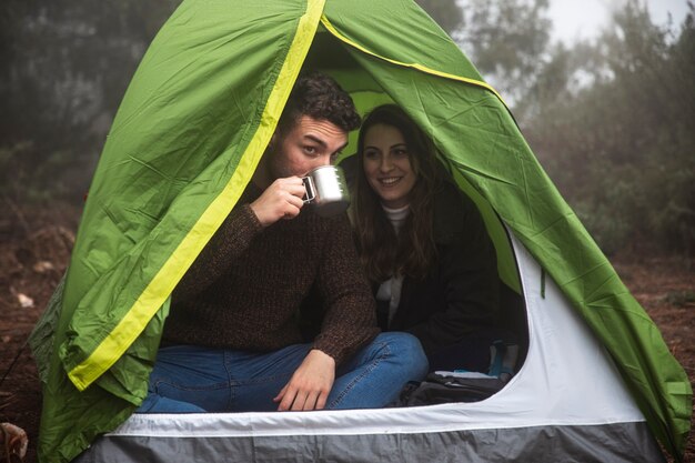 Tiro completo personas bebiendo en carpa