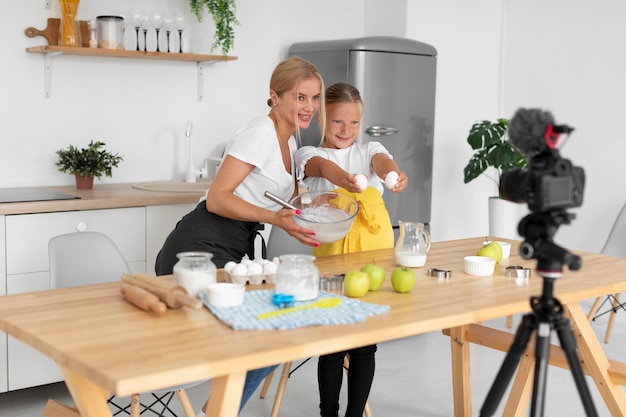 Tiro completo sonriente niña y mujer cocinando