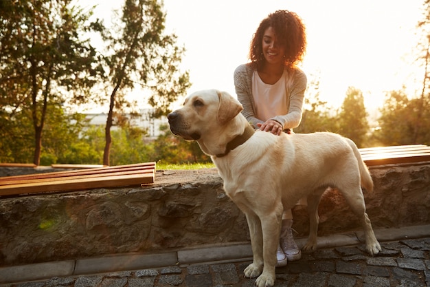 Tiro de cuerpo entero de perro blanco bonito con dueño en park walking