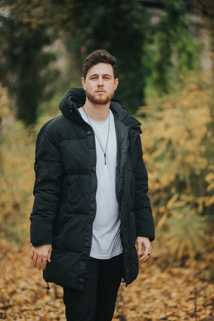 Tiro de enfoque superficial de un hombre joven y atractivo posando en un bosque