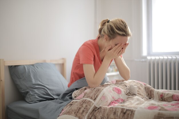 Tiro de enfoque superficial de una mujer llorando que está acostada en la cama