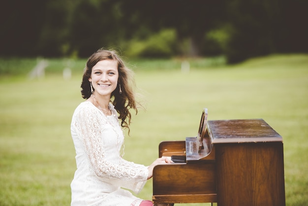 Foto gratuita tiro de enfoque superficial de una mujer tocando el piano mientras sonríe a la cámara