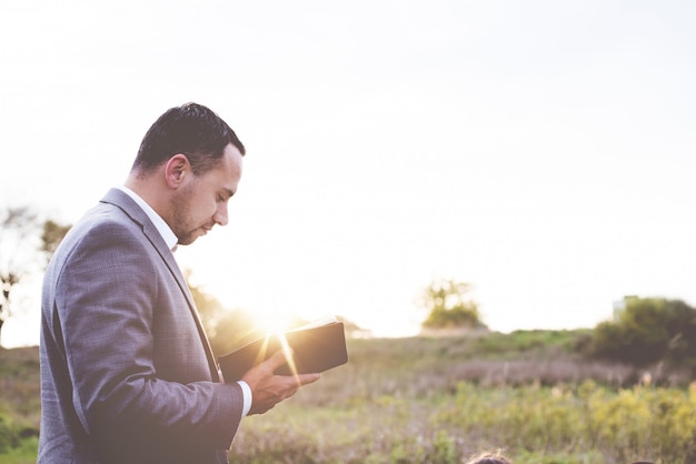 Foto gratuita tiro de enfoque superficial de una persona bien vestida leyendo la biblia