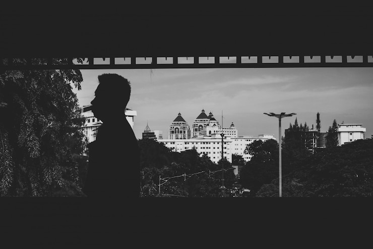 Foto gratuito tiro de escala de grises de un hombre con algunos edificios