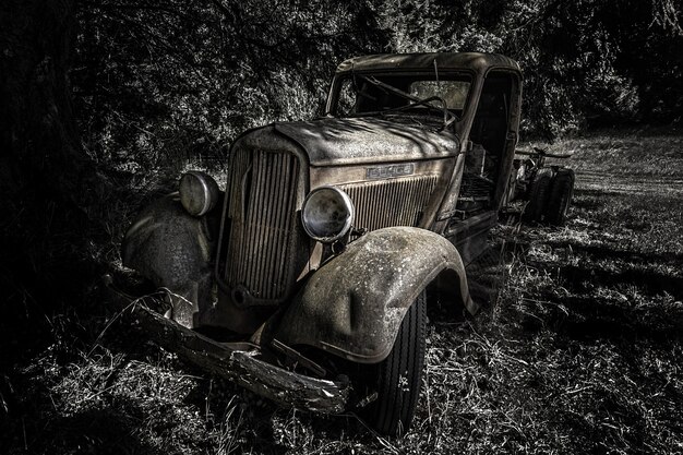 Tiro en escala de grises de un viejo coche retro en el bosque durante el día