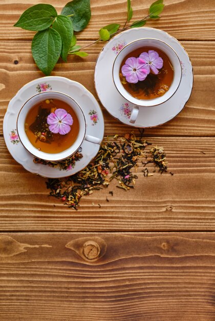 Tiro estético de tazas de té con flores en el interior sobre una mesa de madera