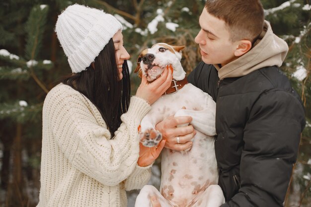 Tiro de estilo de vida de pareja en bosque nevado con perro