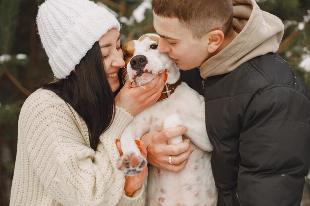 Tiro de estilo de vida de pareja en bosque nevado con perro