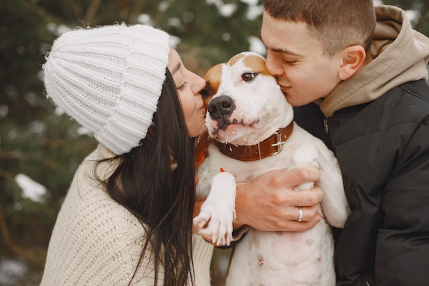 Tiro de estilo de vida de pareja en bosque nevado con perro