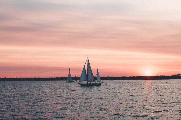 Tiro hermoso paisaje de veleros en el mar bajo el cielo rosado