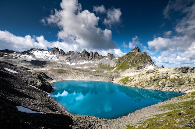 Tiro horizontal de cuerpo de agua rodeado de montañas rocosas bajo el hermoso cielo nublado