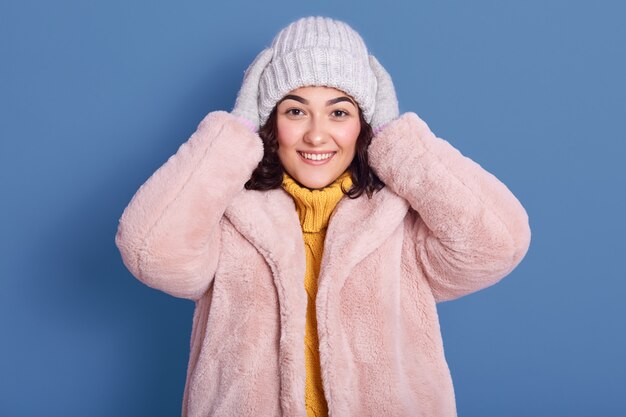 Tiro horizontal de hermosa mujer alegre con abrigo de piel sintética