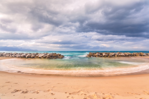 Tiro horizontal de una hermosa playa con rocas bajo el impresionante cielo nublado