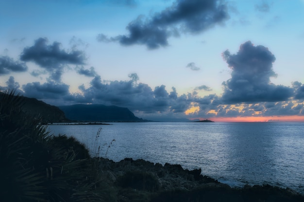 Tiro horizontal del mar en calma bajo el cielo nublado loco en la noche