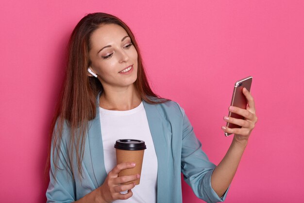 Tiro horizontal de mujer sonriente con cabello largo hermoso haciendo selfie