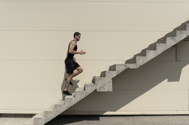 Tiro integral del hombre atlético sano que sube para arriba en las escaleras.
