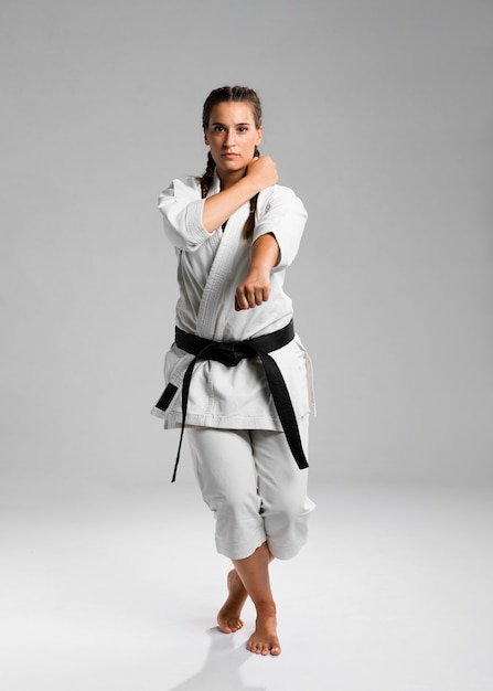 Foto gratuita tiro integral de una mujer con cinturón negro y kimono practicando karate