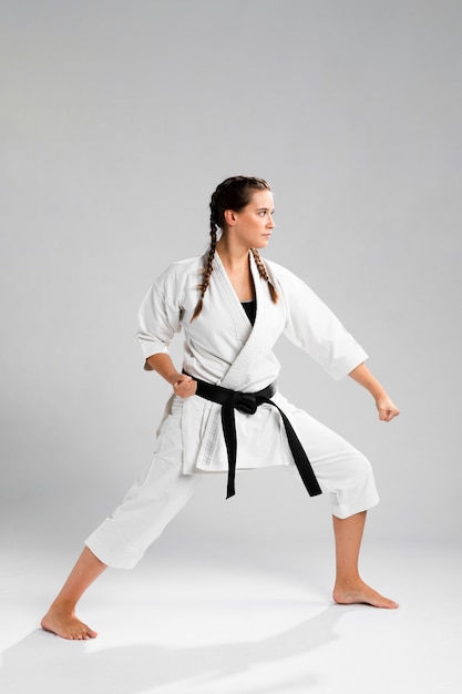 Tiro integral de una mujer con cinturón negro y kimono practicando karate