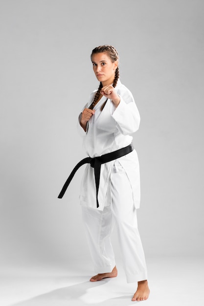 Tiro integral de una mujer con cinturón negro y kimono practicando karate