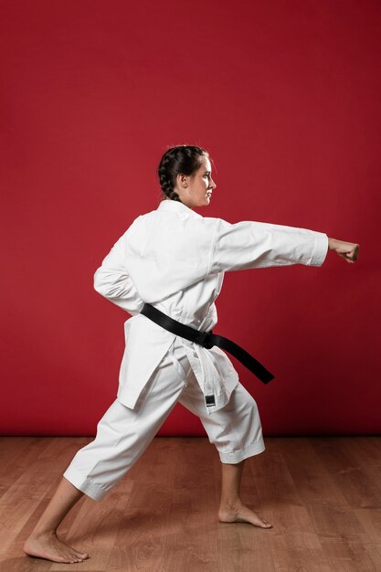 Tiro integral de una mujer con cinturón negro y kimono practicando karate