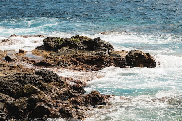 Tiro largo de agua ondulada en la costa rocosa