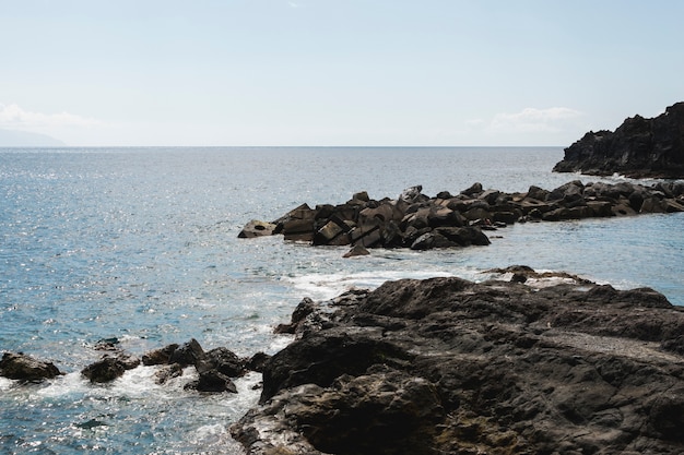 Tiro largo de agua ondulada en la costa rocosa