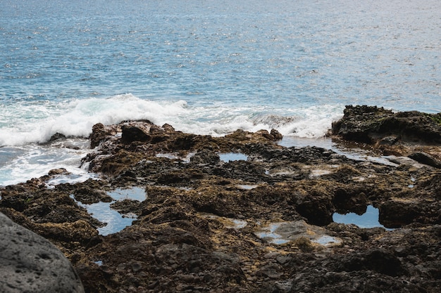 Tiro largo de agua ondulada en la costa rocosa