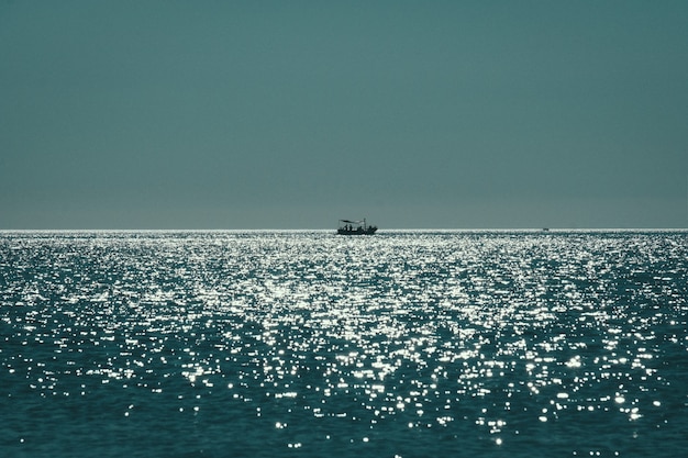 Tiro de largo alcance de un barco que navega en el mar reflejando el sol