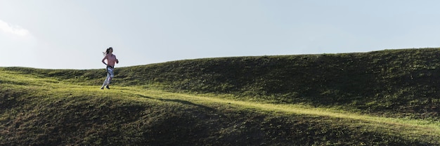 Tiro largo hembra joven corriendo en la naturaleza