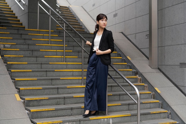 Tiro largo de hermosa mujer de negocios en escaleras