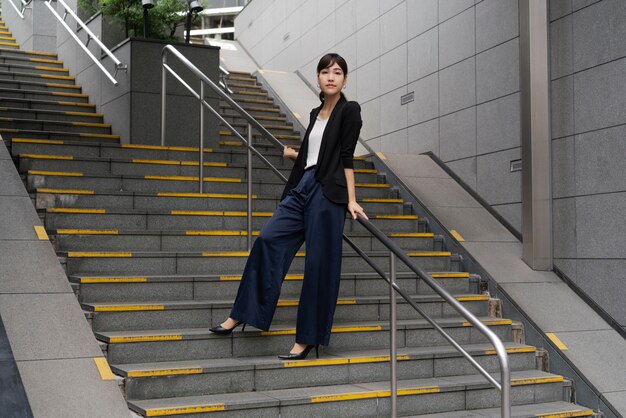 Tiro largo de hermosa mujer de negocios en escaleras